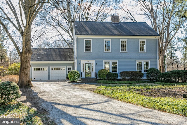 view of front of property featuring an attached garage, a chimney, and driveway