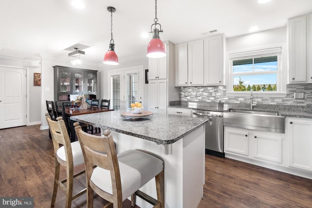 kitchen with tasteful backsplash, a breakfast bar area, dark wood-style flooring, stainless steel dishwasher, and a sink