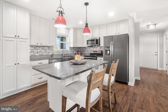 kitchen with a sink, dark wood finished floors, a center island, appliances with stainless steel finishes, and white cabinets