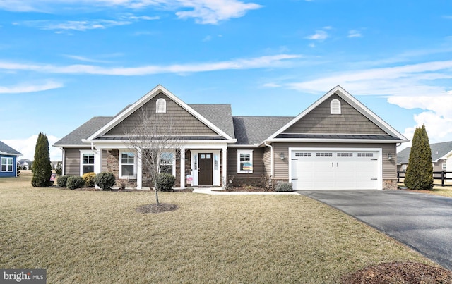 view of front of house with a front yard, a garage, stone siding, driveway, and a standing seam roof