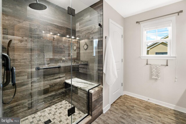 full bathroom featuring baseboards, wood finished floors, and a shower stall