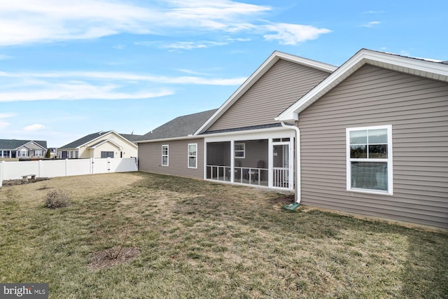 back of house featuring a yard, a fenced backyard, and a sunroom