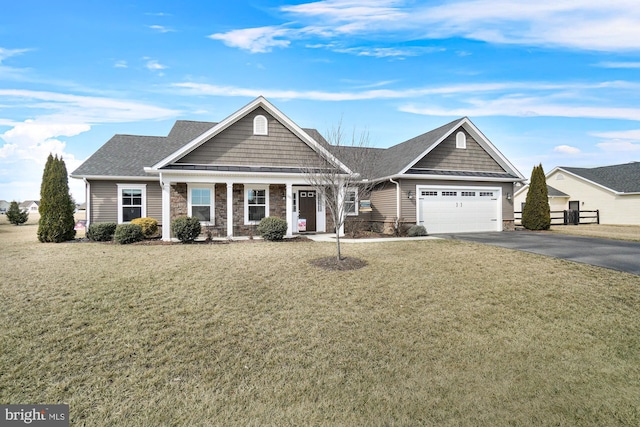 view of front of house featuring aphalt driveway, stone siding, an attached garage, and a front lawn