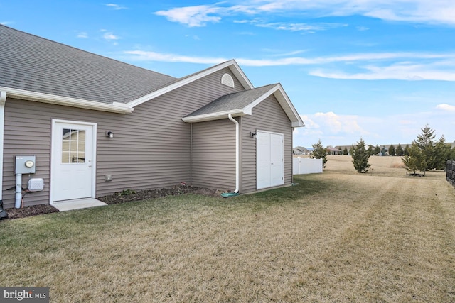 exterior space featuring a shingled roof and a yard