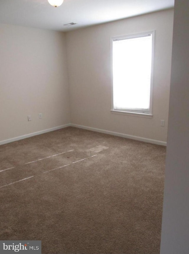 spare room featuring baseboards, carpet floors, and visible vents