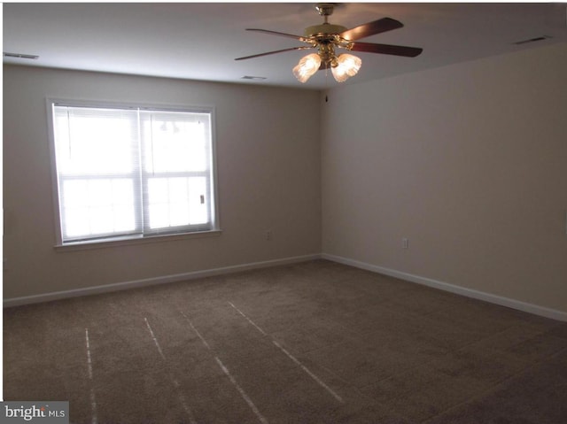 carpeted empty room with visible vents, ceiling fan, and baseboards