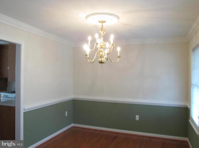 unfurnished dining area featuring a notable chandelier, ornamental molding, baseboards, and wood finished floors