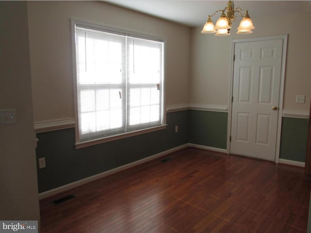 unfurnished room featuring hardwood / wood-style floors, visible vents, baseboards, and a chandelier