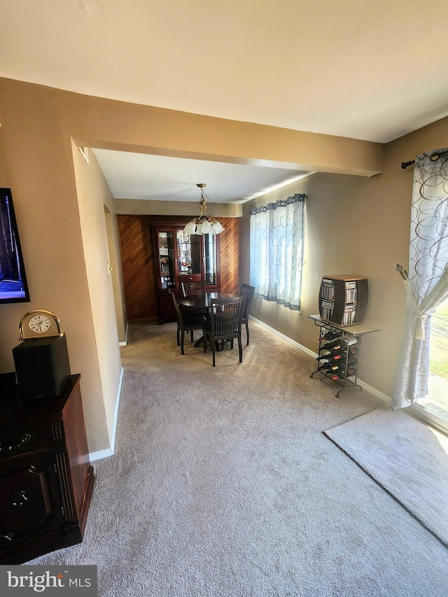 unfurnished dining area with carpet flooring, beamed ceiling, and baseboards