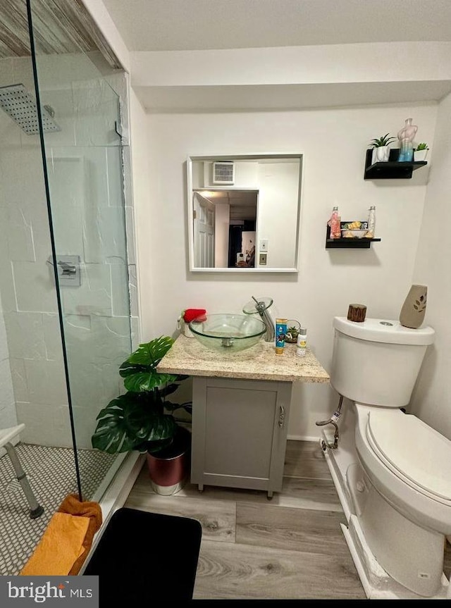 full bath with a shower stall, toilet, vanity, and wood finished floors