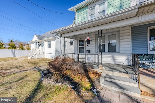 doorway to property featuring fence and covered porch