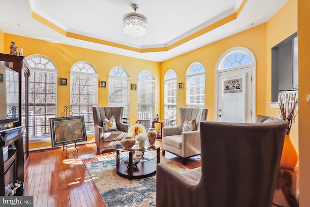 interior space featuring a chandelier, ornamental molding, a raised ceiling, and hardwood / wood-style flooring