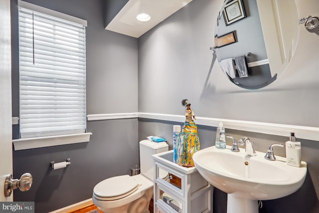 bathroom with a healthy amount of sunlight, toilet, and a sink