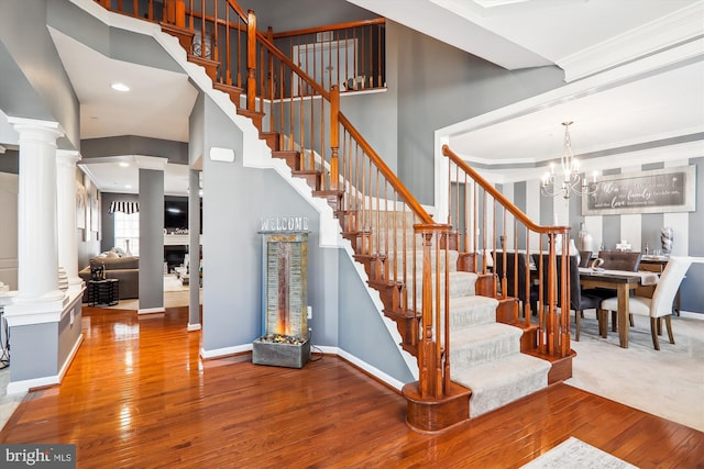 stairs featuring hardwood / wood-style flooring, decorative columns, and baseboards