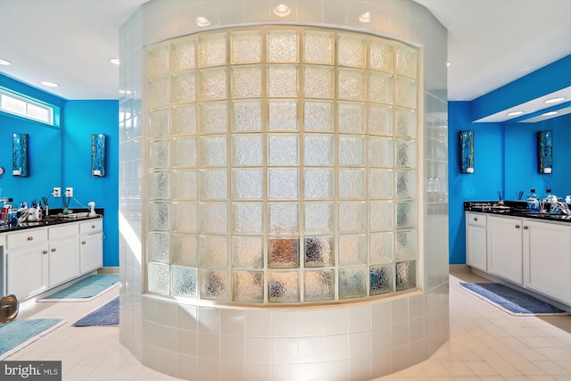 full bath featuring a sink, two vanities, walk in shower, and tile patterned flooring