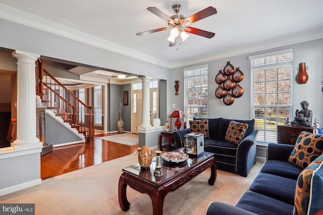 living room featuring crown molding, stairway, decorative columns, and plenty of natural light