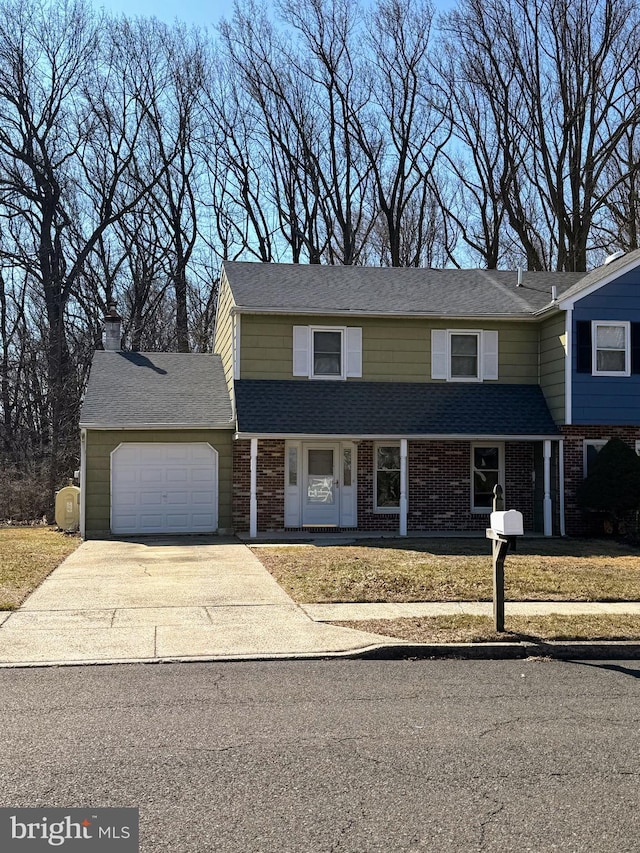 traditional-style home featuring driveway, roof with shingles, an attached garage, a front lawn, and brick siding