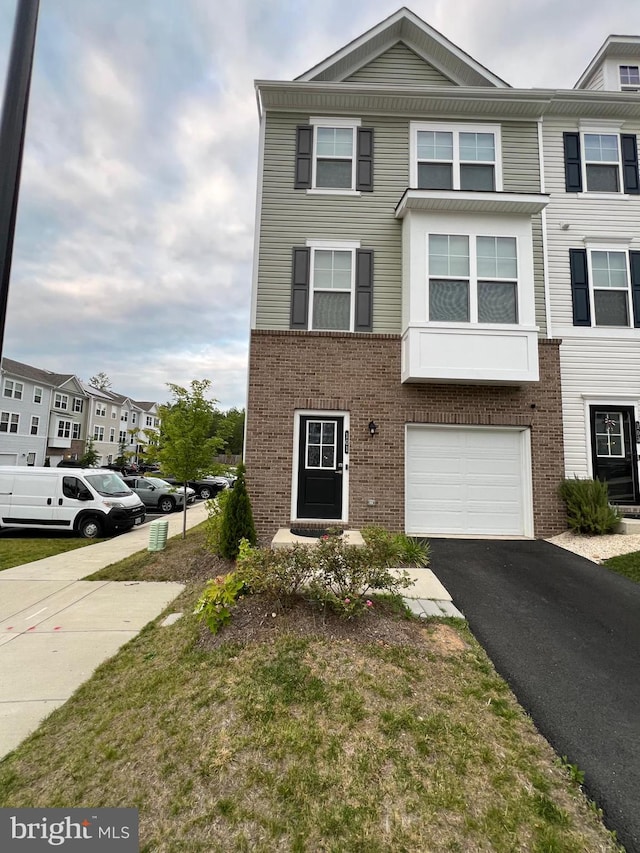 view of property featuring brick siding, an attached garage, and driveway