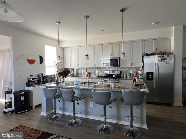 kitchen featuring a breakfast bar area, an island with sink, tasteful backsplash, and appliances with stainless steel finishes