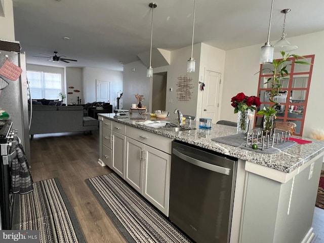 kitchen with pendant lighting, a sink, stainless steel dishwasher, open floor plan, and dark wood-style flooring