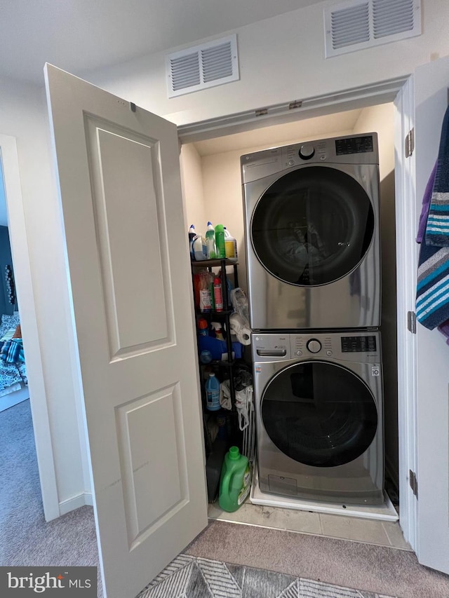 clothes washing area featuring stacked washer / dryer, carpet flooring, laundry area, and visible vents