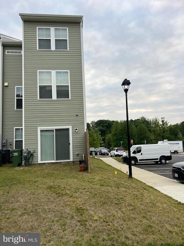 back of house featuring a yard and uncovered parking