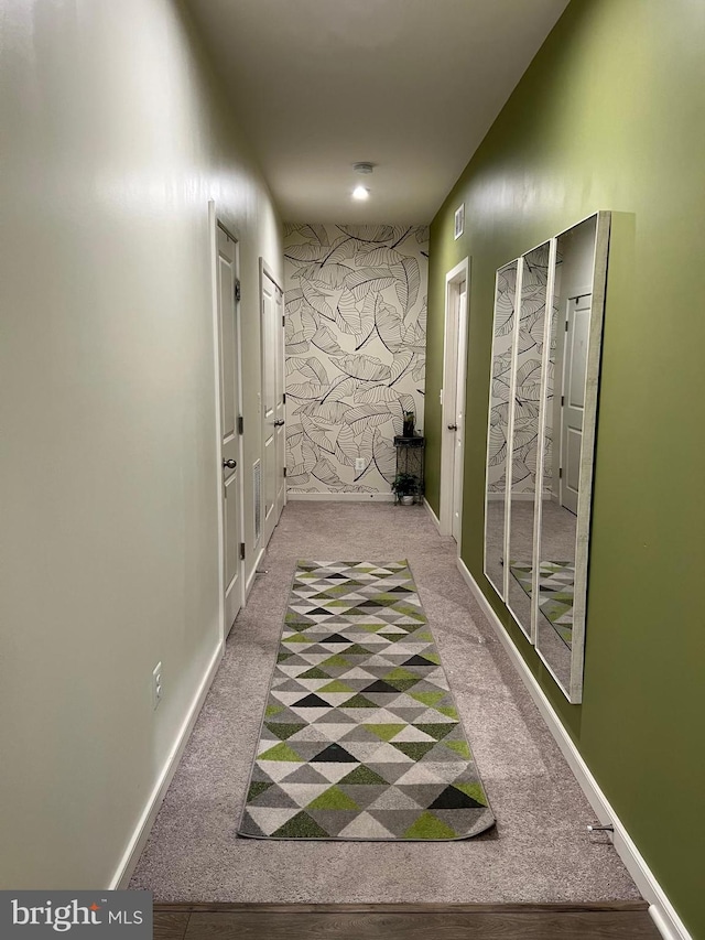 hallway featuring carpet flooring and baseboards