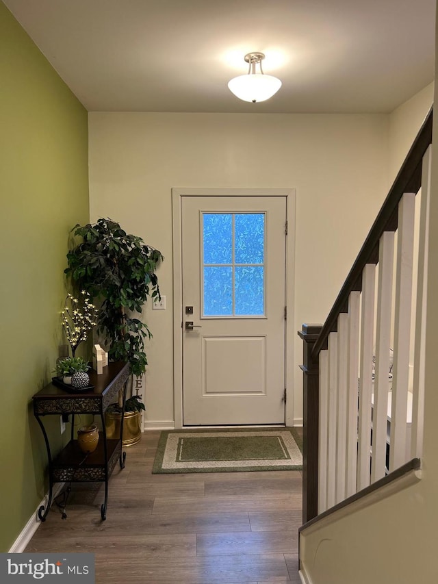 foyer entrance featuring stairway, baseboards, and wood finished floors