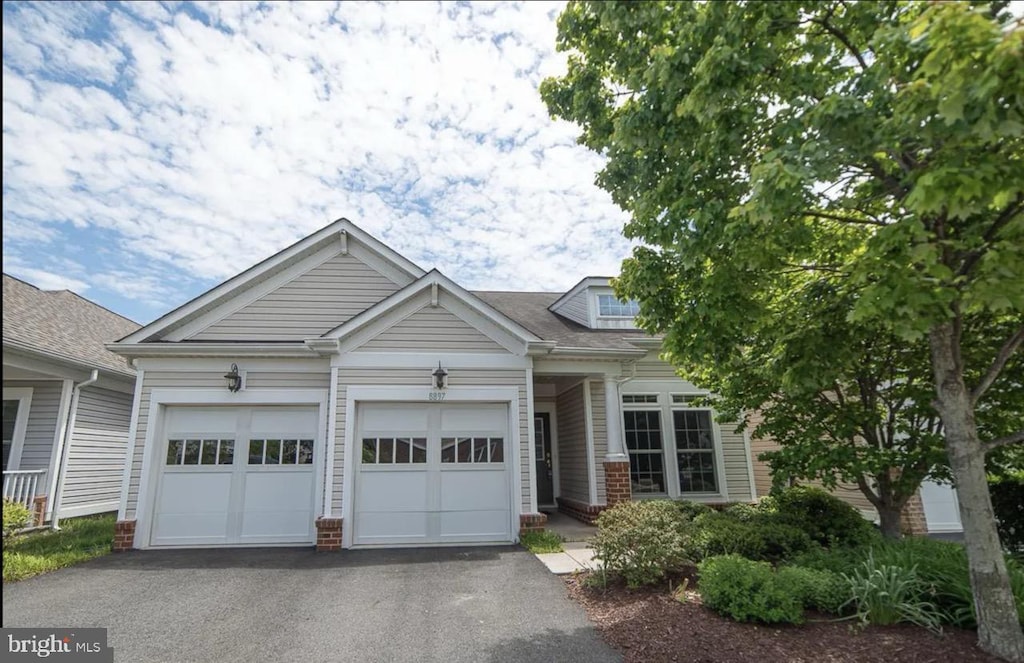 view of front of property featuring aphalt driveway, brick siding, and a garage