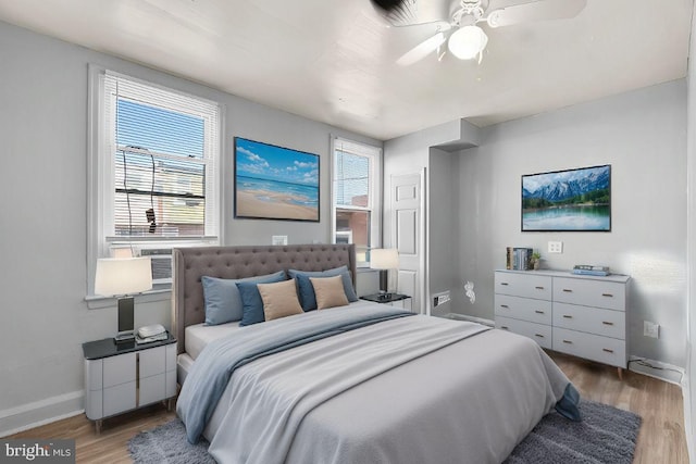 bedroom with multiple windows, ceiling fan, baseboards, and wood finished floors