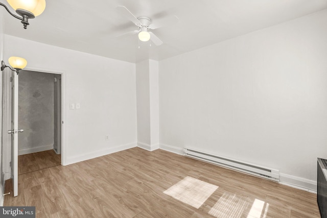 spare room with wood finished floors, baseboards, and a baseboard radiator