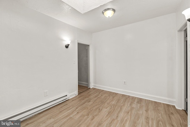 unfurnished room featuring a textured ceiling, baseboards, light wood-type flooring, and a baseboard radiator