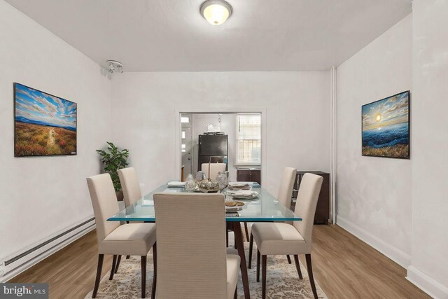 dining area featuring baseboards, light wood finished floors, and a baseboard radiator