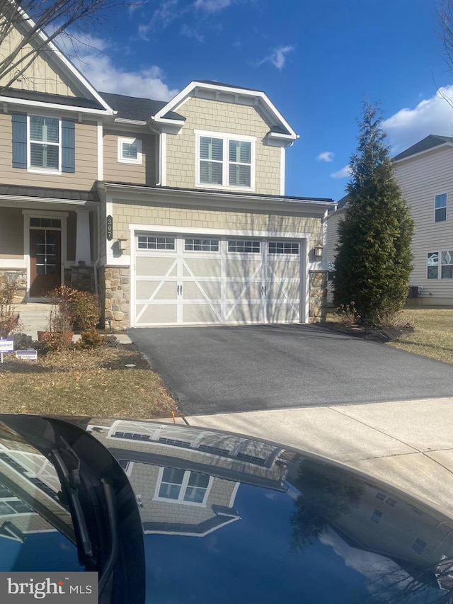 view of front of property with aphalt driveway, stone siding, and a garage