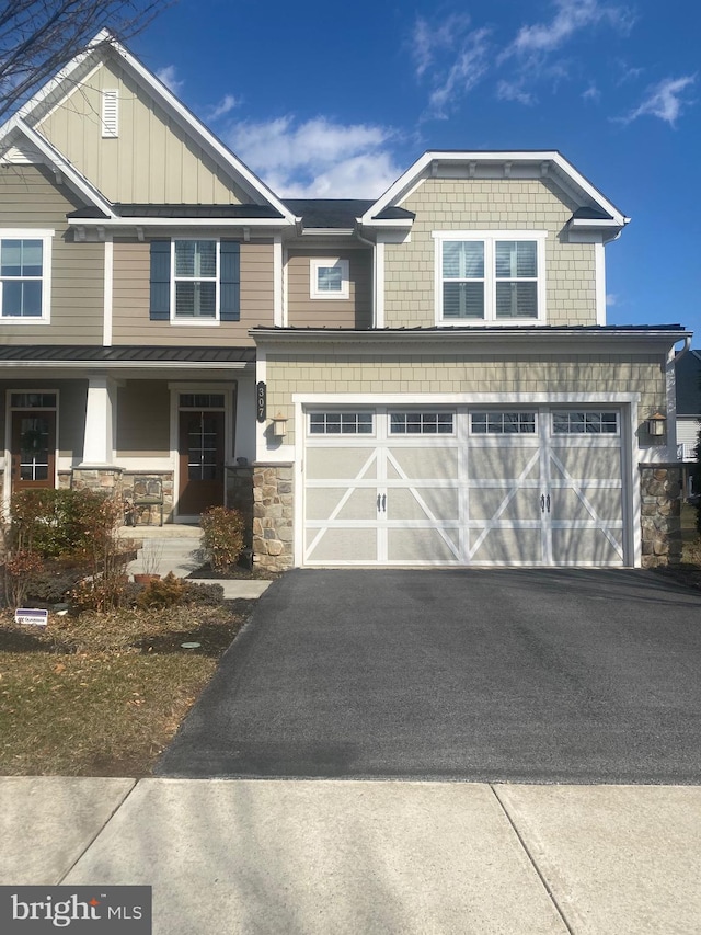 view of front facade featuring driveway, an attached garage, covered porch, stone siding, and board and batten siding