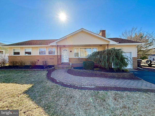 single story home featuring brick siding, a front lawn, aphalt driveway, a chimney, and an attached garage