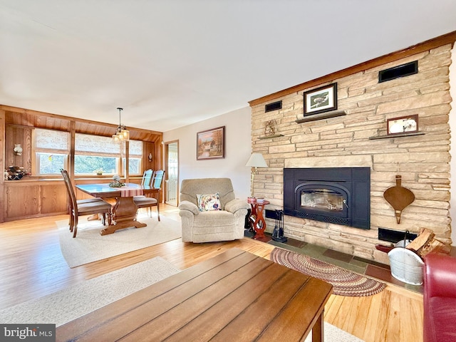 living area with a stone fireplace, wood finished floors, and a healthy amount of sunlight