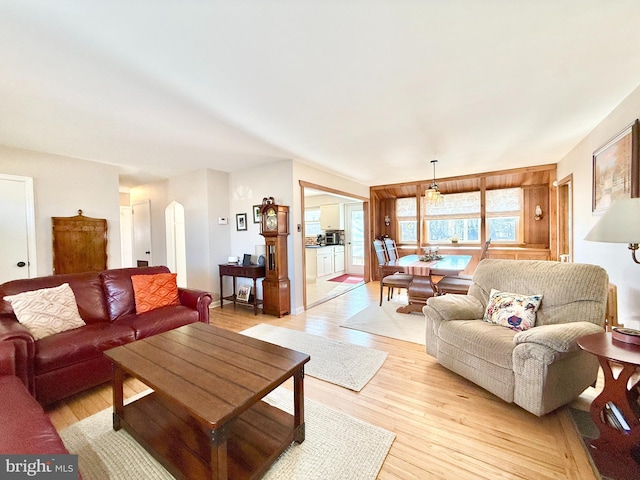 living room featuring arched walkways and light wood-type flooring