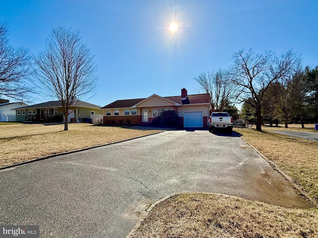 ranch-style house with aphalt driveway, a garage, a front lawn, and a chimney