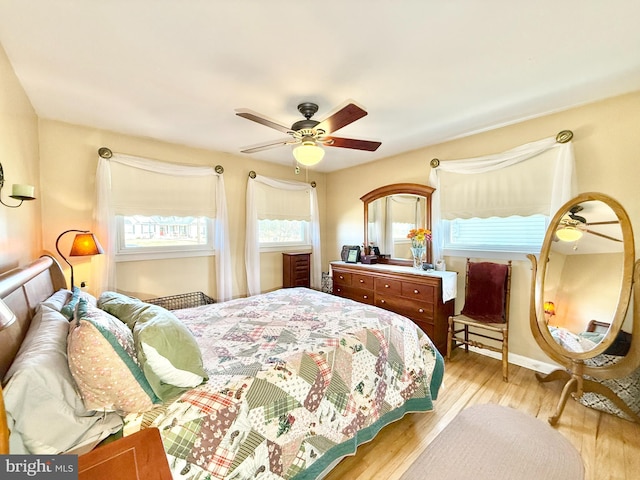 bedroom featuring baseboards, wood finished floors, and a ceiling fan