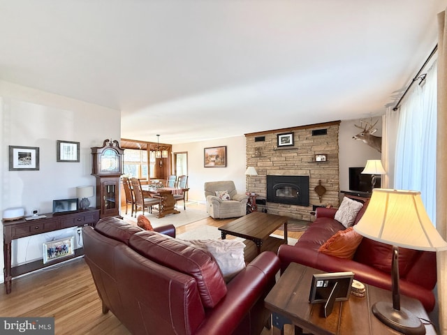 living room featuring a stone fireplace and wood finished floors