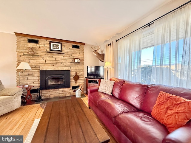 living area featuring a stone fireplace and wood finished floors