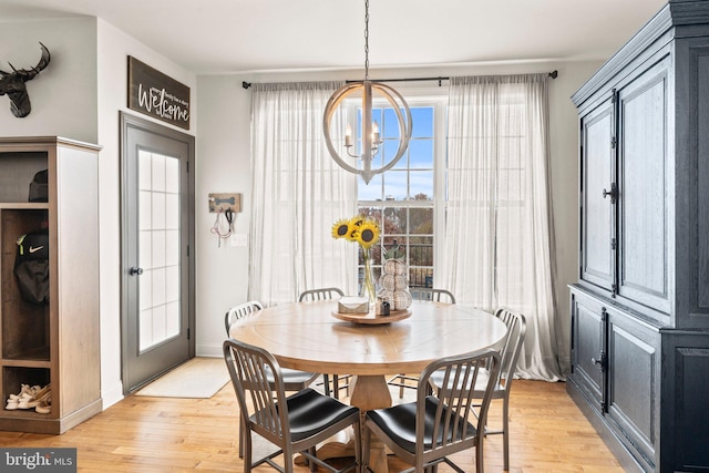 dining area featuring light wood finished floors, plenty of natural light, baseboards, and an inviting chandelier