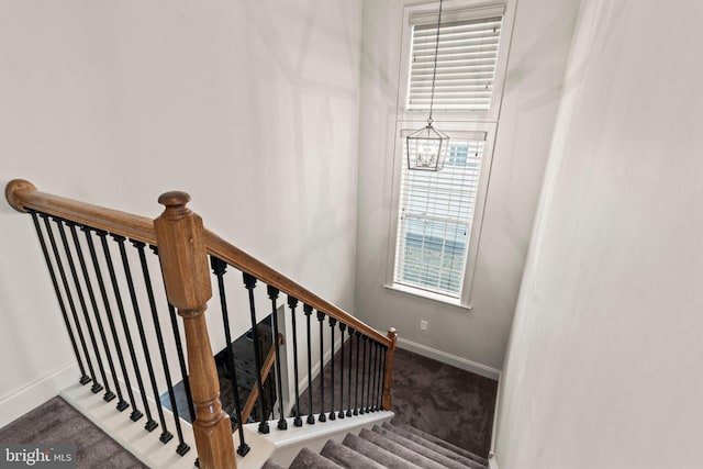 stairway with carpet flooring, baseboards, and a chandelier