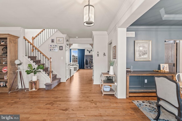 foyer featuring visible vents, light wood-style floors, stairs, and crown molding