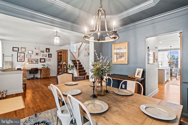 dining area with ornamental molding, a raised ceiling, and wood-type flooring