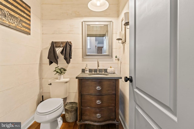 half bathroom featuring vanity, toilet, and wood finished floors