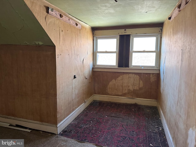 spare room with baseboards and wood walls