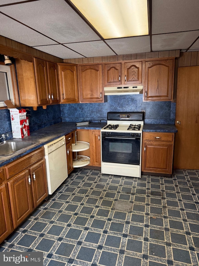 kitchen with range with gas cooktop, dark floors, under cabinet range hood, dishwasher, and brown cabinets