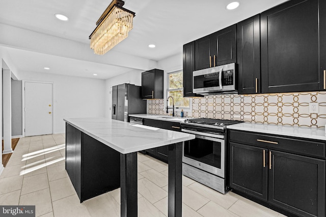 kitchen with a sink, tasteful backsplash, appliances with stainless steel finishes, and dark cabinetry